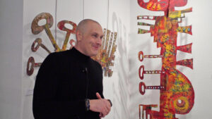 Pietra tout sourire devant une deux de ses œuvres très colorées